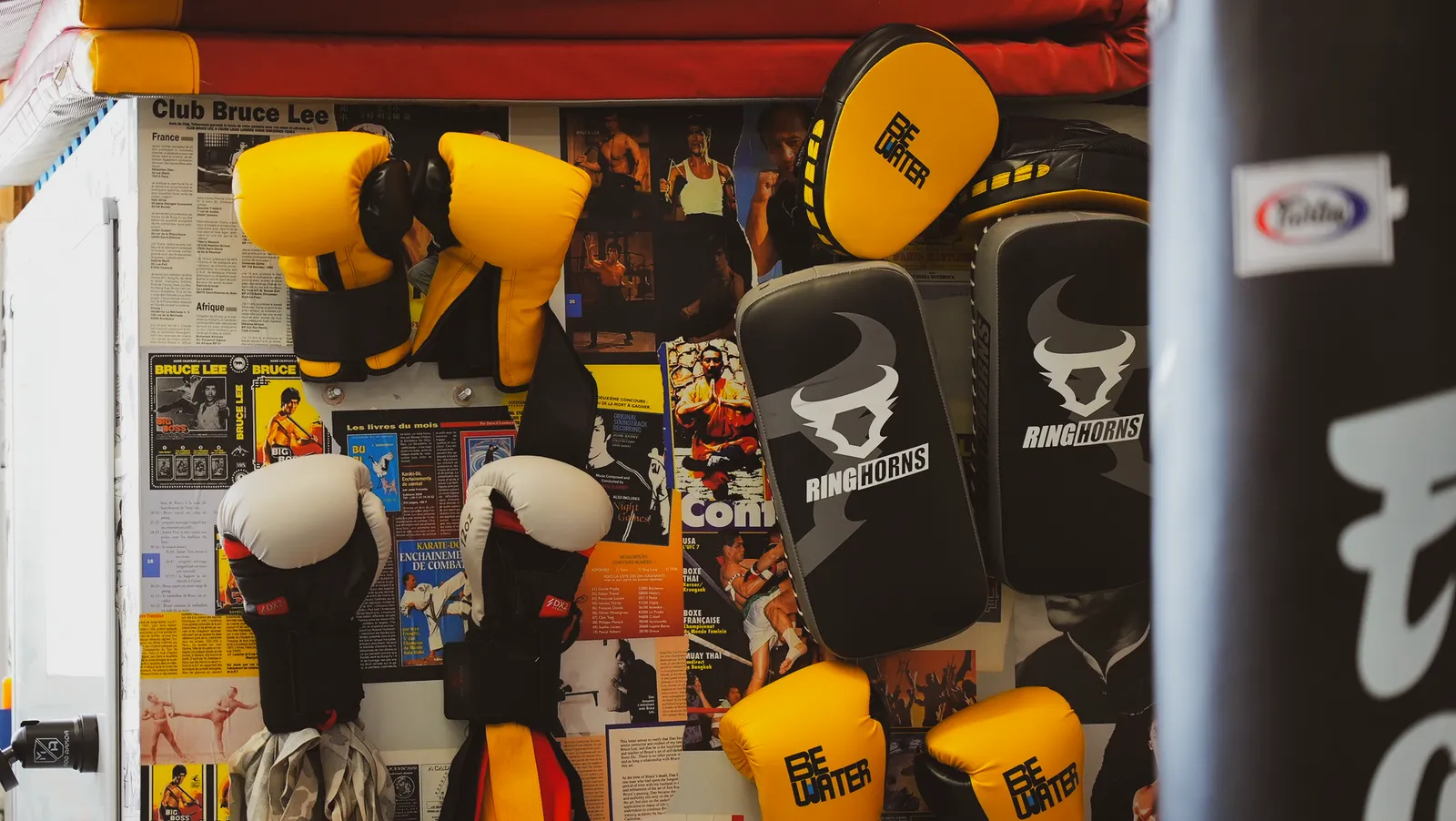 Boxing gloves, focus mitts and a Muay Thai pad on the wall at Be Water Lisboa