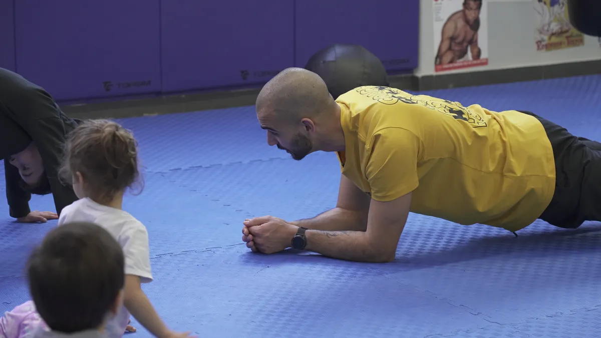 Coach demonstra bear crawl às crianças